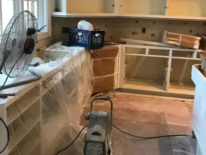 Kitchen cabinets wrapped in plastic while a fan dries out the room