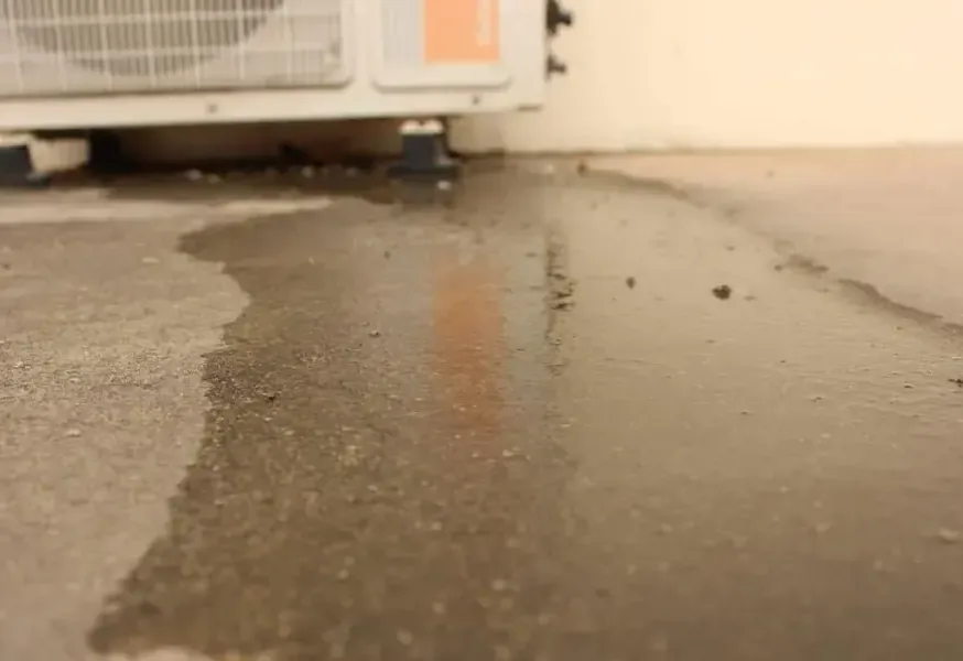 Water spreading over a concrete floor from under an air conditioning unit
