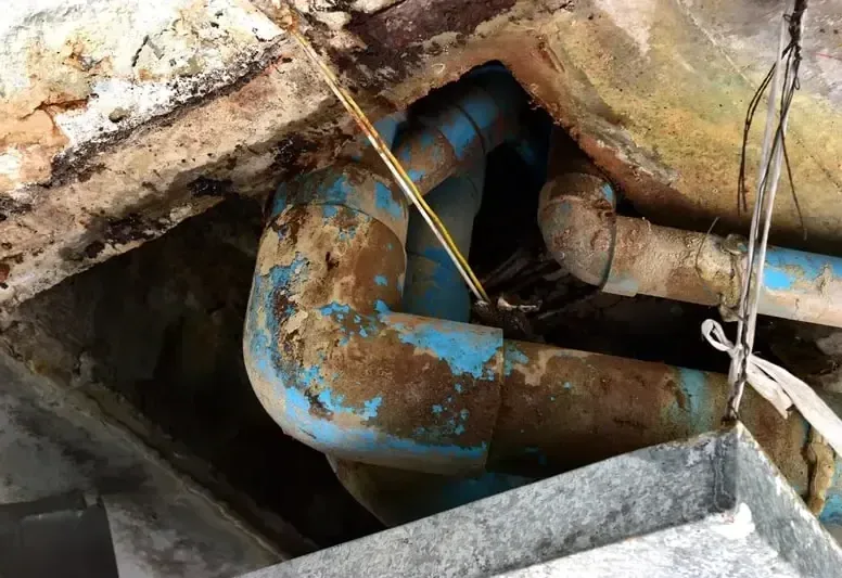 Corroded copper and galvanized pipe exposed beneath a floor after a pipe gave way