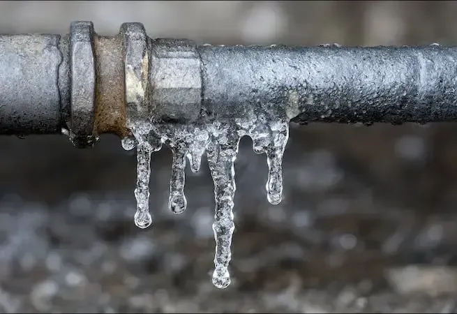 Ice hanging from a frozen metal pipe in a cold snap