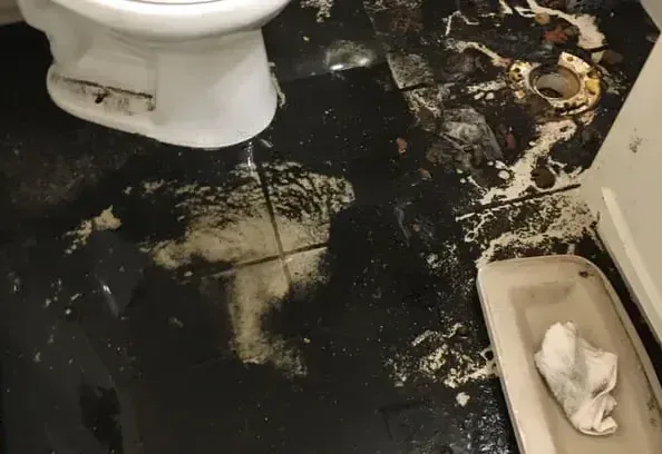 Sewage water spread over a bathroom floor around the toilet
