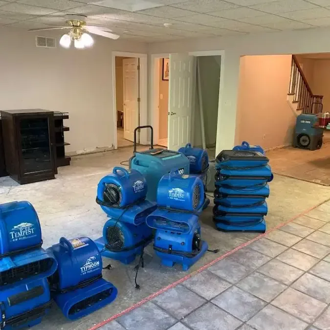 Blue air movers and dehumidifiers stacked on a tile floor, ready for structural drying
